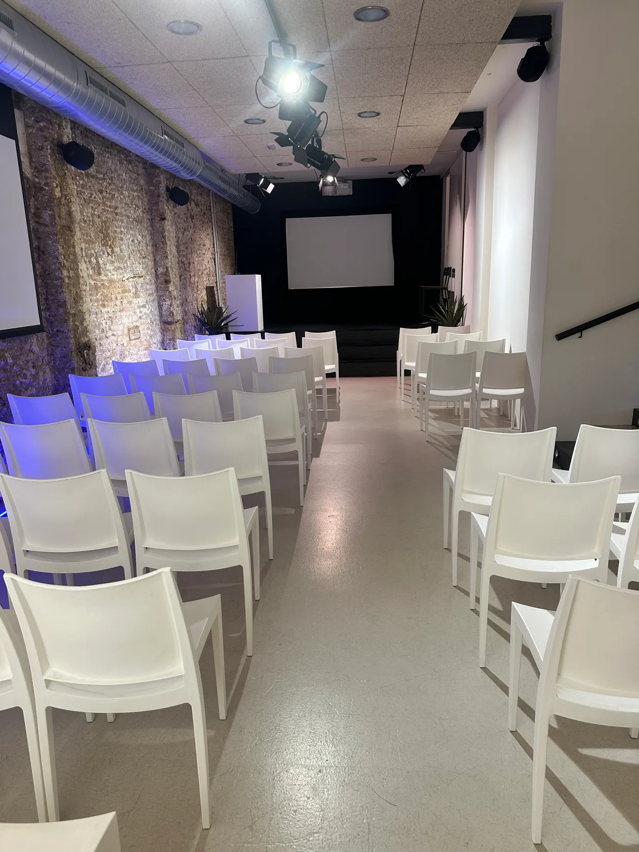 AI Campus event room set up theatre-style with rows of chairs facing the stage and screen.